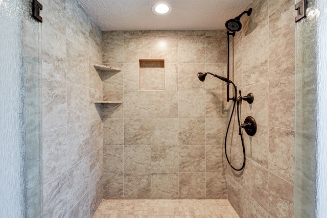 bathroom featuring a textured ceiling and tiled shower