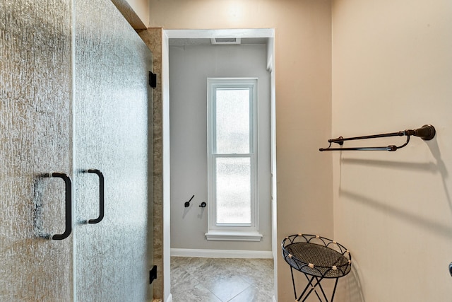 bathroom with a shower with door and tile patterned flooring