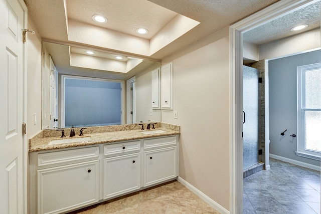 bathroom featuring a raised ceiling, a textured ceiling, an enclosed shower, vanity, and tile patterned flooring