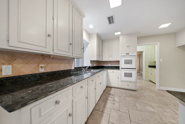 kitchen with decorative backsplash, white double oven, and white cabinets