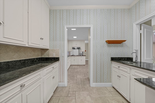 kitchen with tasteful backsplash, dark stone countertops, white cabinetry, and sink