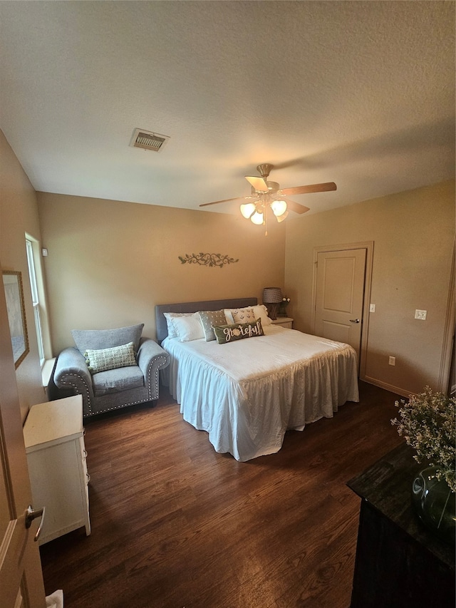 bedroom featuring a textured ceiling, dark wood-type flooring, and ceiling fan