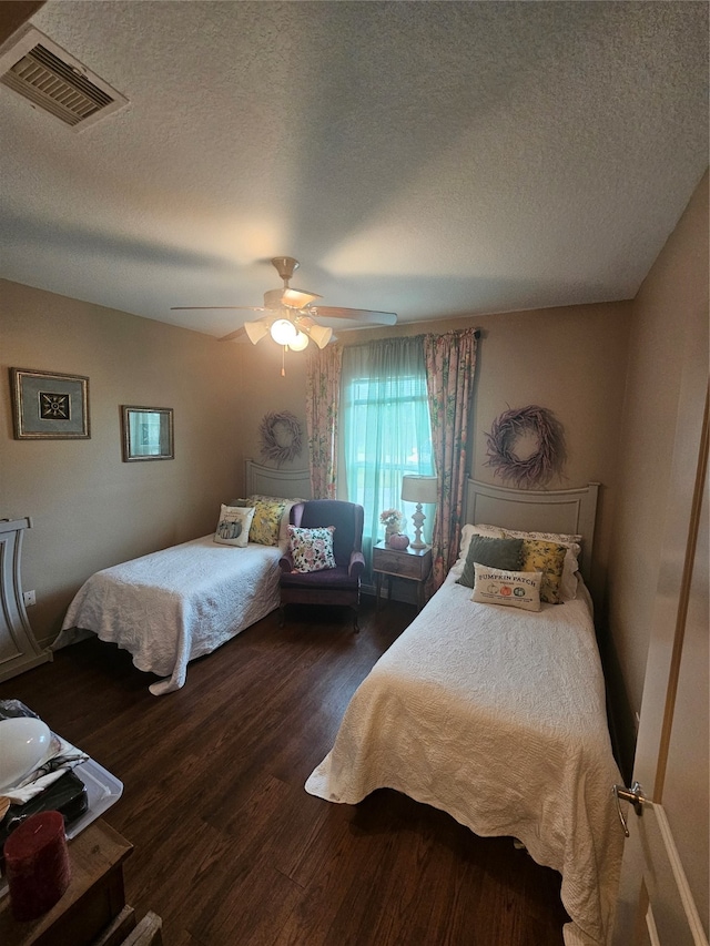 bedroom with dark hardwood / wood-style flooring, a textured ceiling, and ceiling fan