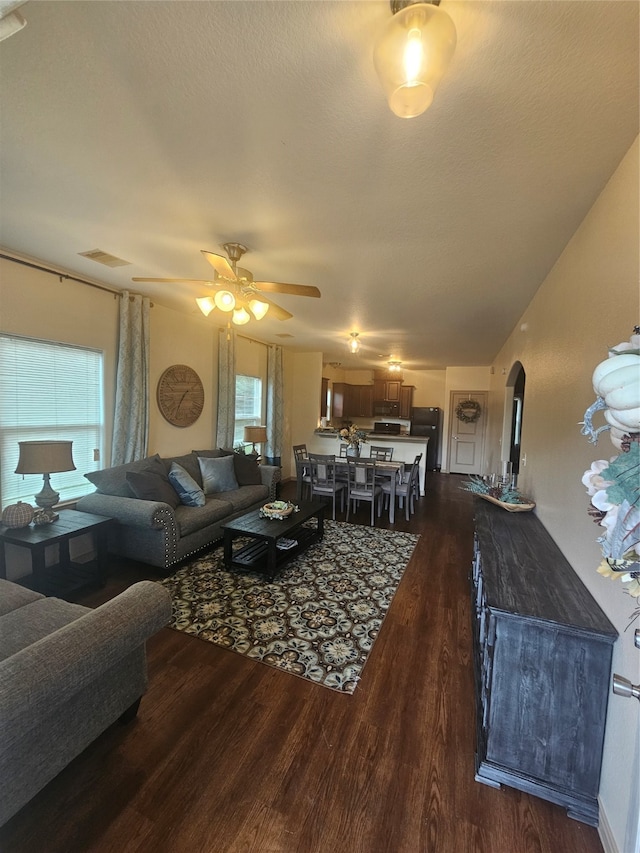 living room with a textured ceiling, dark hardwood / wood-style flooring, and ceiling fan