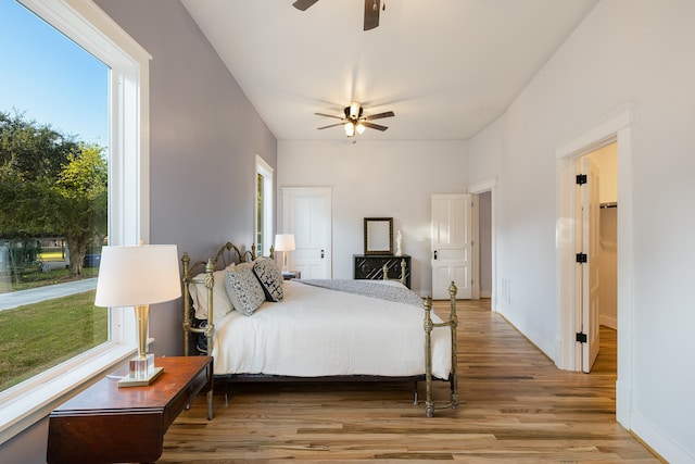 bedroom featuring ceiling fan, hardwood / wood-style flooring, and multiple windows