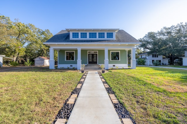 bungalow featuring covered porch, a front yard, an outbuilding, and a garage