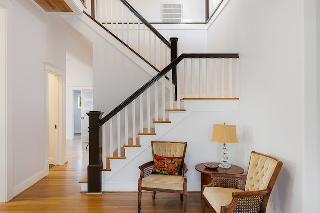 staircase featuring a towering ceiling and hardwood / wood-style floors