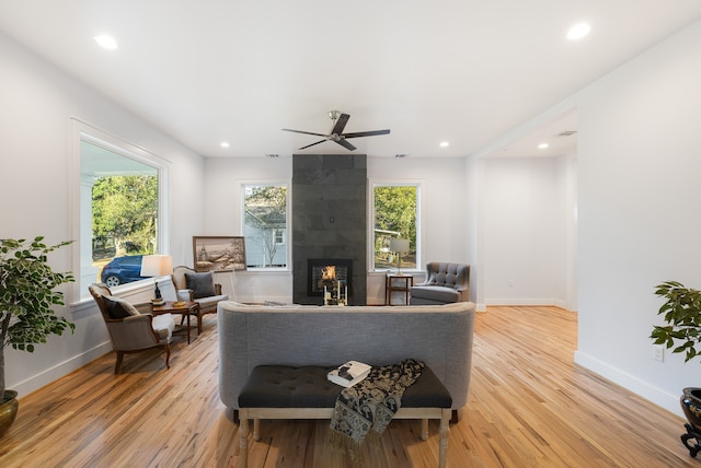 living room with plenty of natural light, a tiled fireplace, and light wood-type flooring