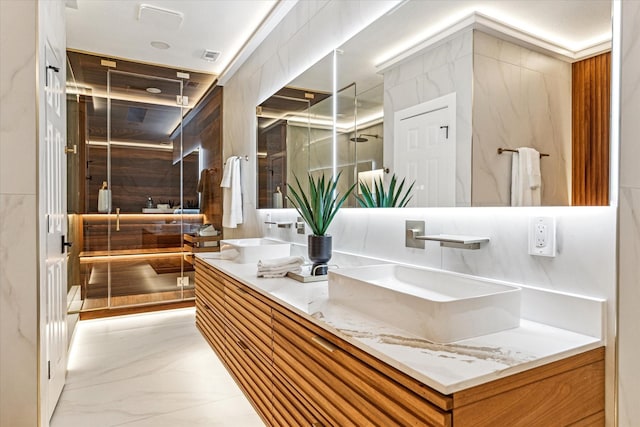 bathroom with vanity, a shower with shower door, and tile walls