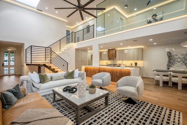 living room with light hardwood / wood-style floors and a towering ceiling