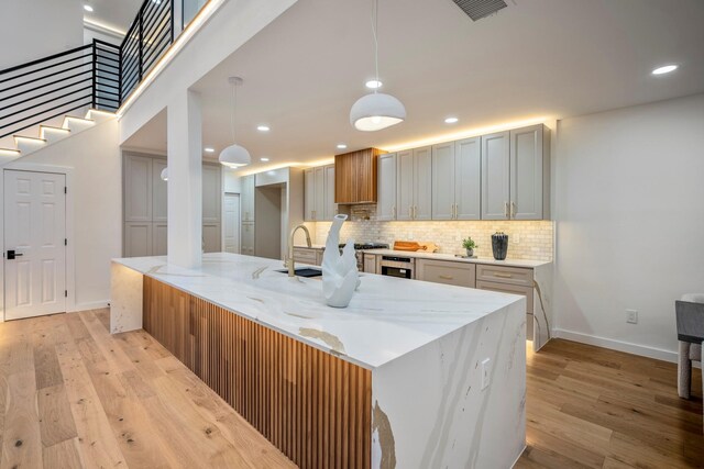 kitchen featuring wine cooler, decorative light fixtures, white cabinets, light stone counters, and light hardwood / wood-style floors