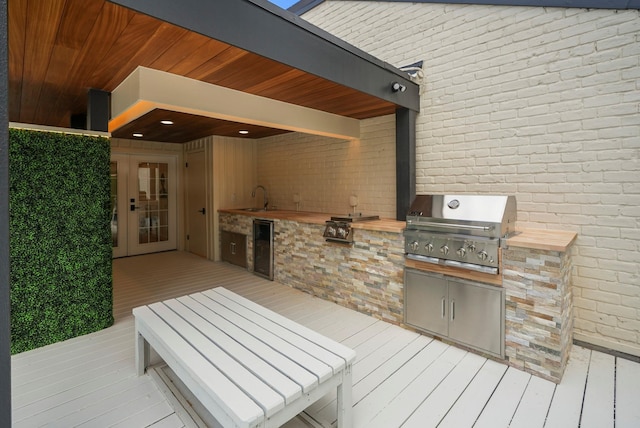 wooden deck with sink, exterior kitchen, and area for grilling