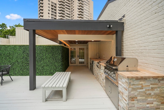 view of patio / terrace featuring french doors, grilling area, an outdoor kitchen, sink, and a deck