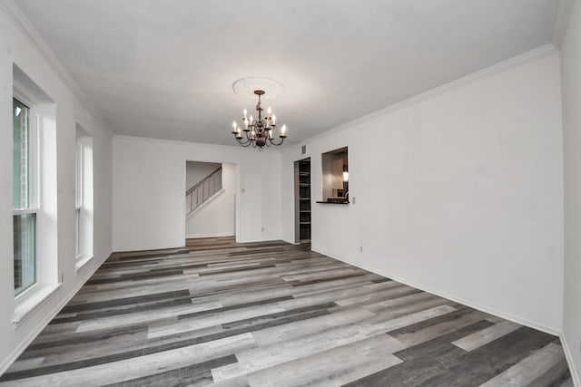 empty room with hardwood / wood-style flooring, crown molding, and a notable chandelier