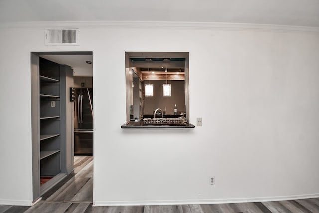 unfurnished room with bar area, crown molding, and dark wood-type flooring