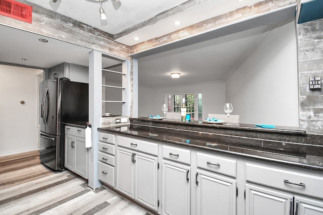 kitchen featuring beam ceiling, stainless steel fridge, dark stone counters, light hardwood / wood-style floors, and decorative backsplash