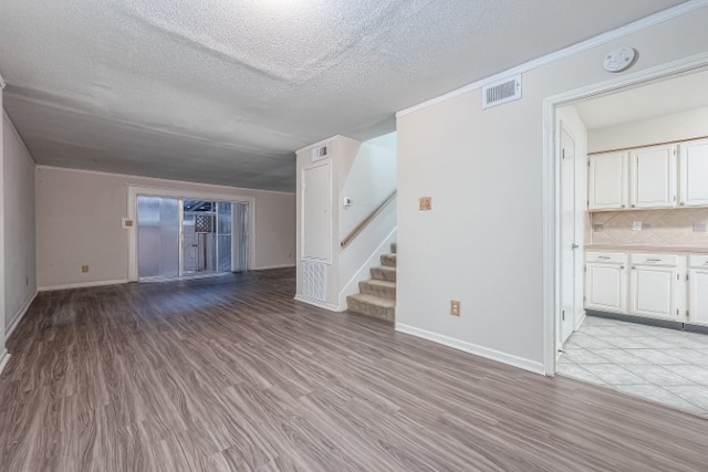 unfurnished living room with light hardwood / wood-style floors and a textured ceiling