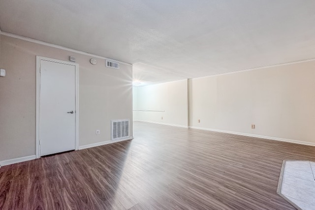 spare room with dark hardwood / wood-style floors and crown molding