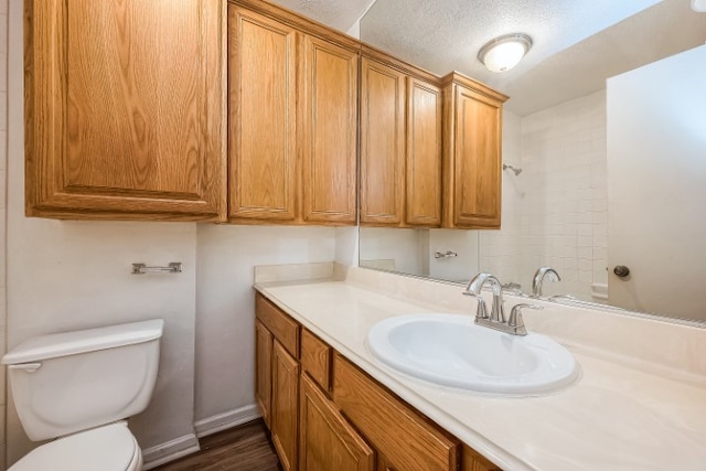 bathroom with toilet, hardwood / wood-style floors, vanity, and a textured ceiling