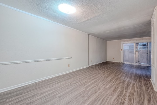 empty room featuring a textured ceiling, hardwood / wood-style flooring, and crown molding