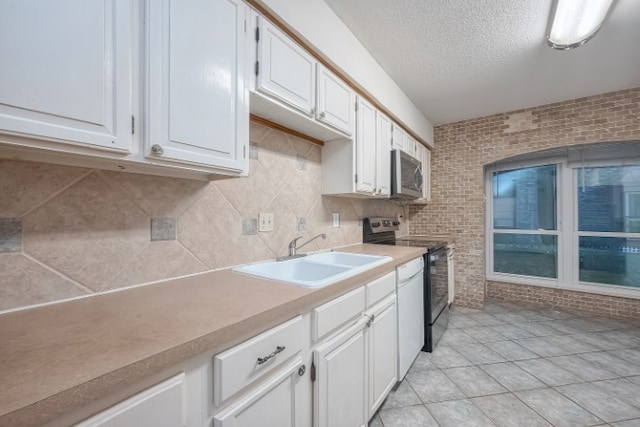 kitchen featuring white cabinetry, sink, brick wall, light tile patterned floors, and electric range