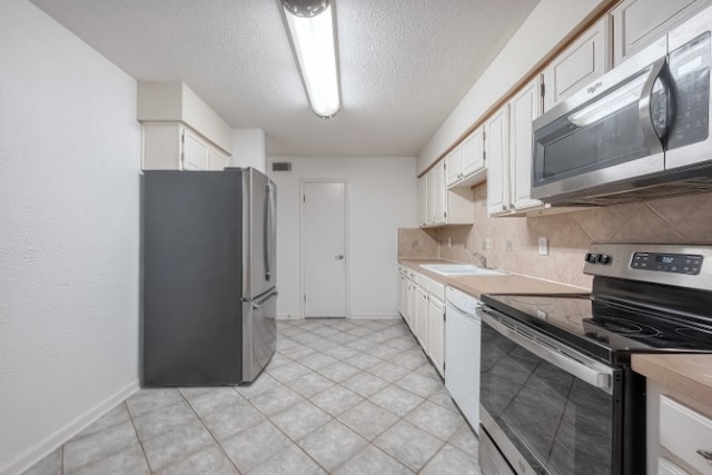 kitchen with white cabinetry, appliances with stainless steel finishes, a textured ceiling, sink, and decorative backsplash