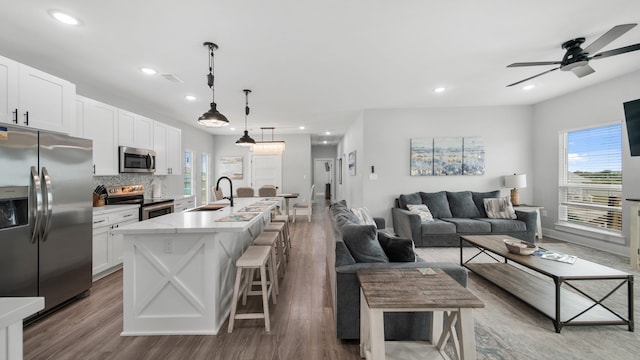 kitchen featuring appliances with stainless steel finishes, white cabinetry, a kitchen island with sink, and a kitchen breakfast bar