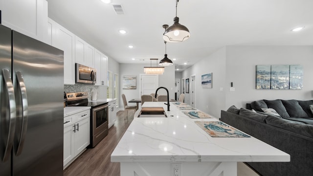 kitchen with hanging light fixtures, dark hardwood / wood-style flooring, an island with sink, white cabinetry, and stainless steel appliances