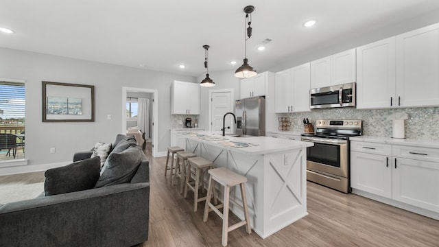 kitchen with a kitchen breakfast bar, white cabinets, a kitchen island with sink, and stainless steel appliances