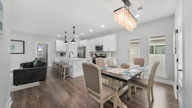 dining area with a notable chandelier, a healthy amount of sunlight, and dark hardwood / wood-style flooring