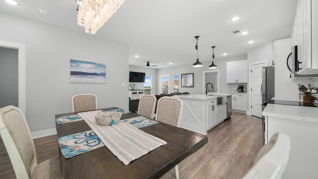 dining area featuring hardwood / wood-style flooring, sink, and ceiling fan with notable chandelier