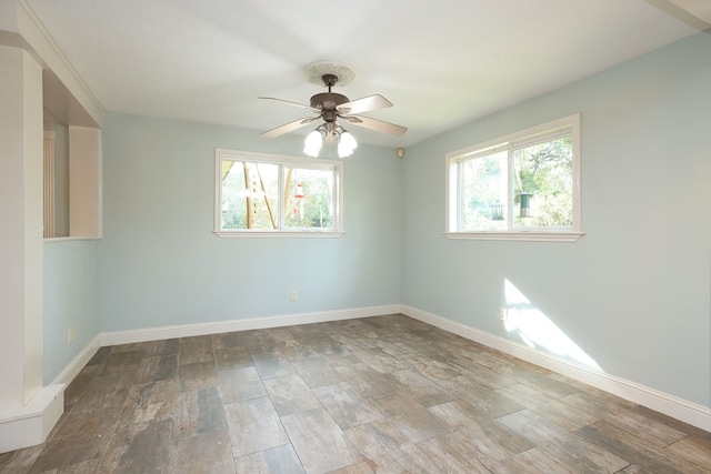 spare room with a wealth of natural light, wood-type flooring, and ceiling fan