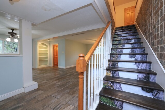 stairs with hardwood / wood-style floors and brick wall