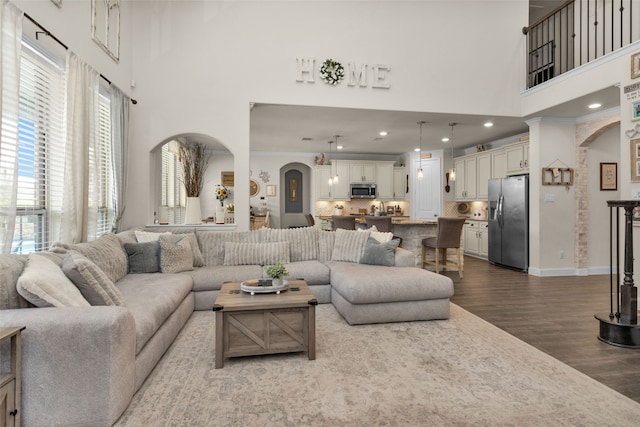 living room with a towering ceiling, ornamental molding, and hardwood / wood-style flooring