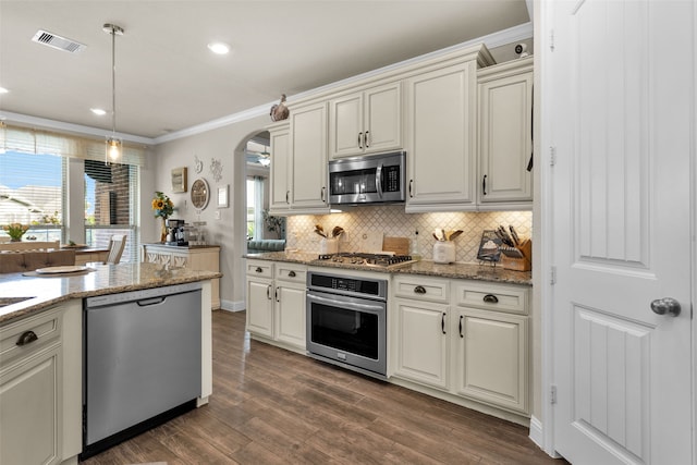 kitchen featuring hanging light fixtures, light stone countertops, dark hardwood / wood-style floors, crown molding, and stainless steel appliances