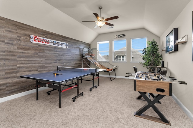 recreation room with ceiling fan, wood walls, carpet, and lofted ceiling