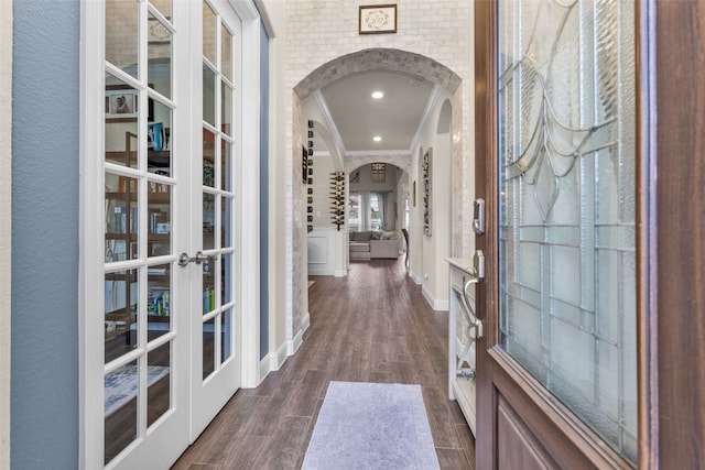 interior space featuring brick wall, french doors, dark wood-type flooring, and ornamental molding