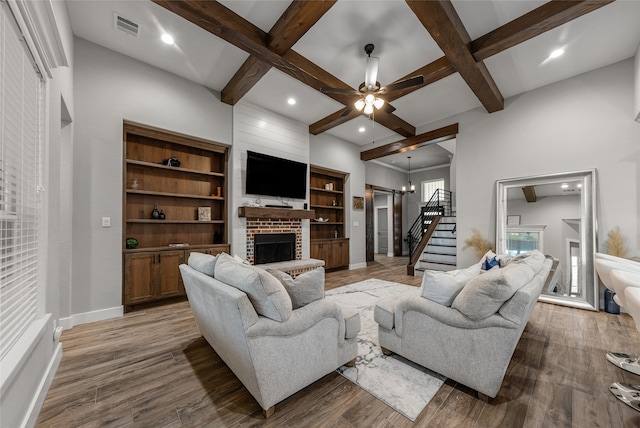 living room with wood-type flooring, beamed ceiling, and a brick fireplace