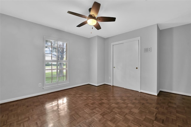 unfurnished bedroom featuring ceiling fan, dark parquet flooring, and a closet