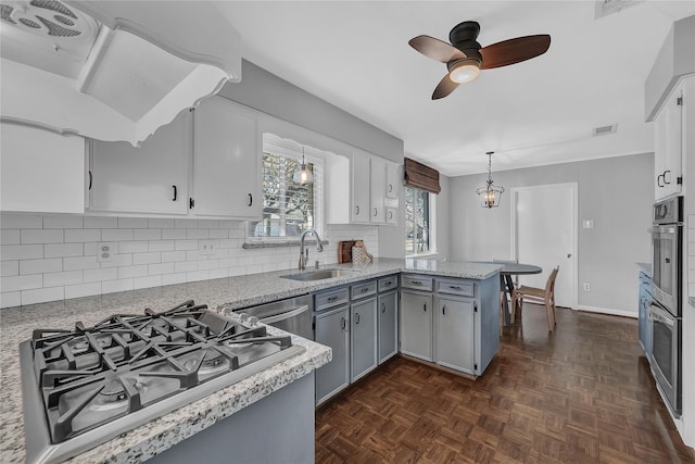 kitchen featuring pendant lighting, sink, dark parquet floors, kitchen peninsula, and cooktop