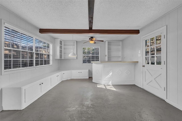 interior space with ceiling fan, beam ceiling, concrete flooring, and a textured ceiling