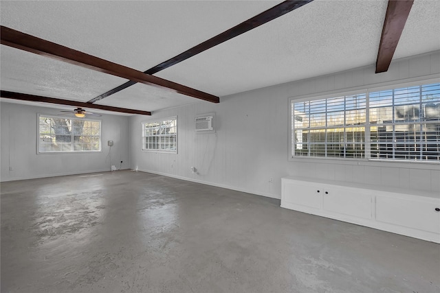 unfurnished living room with a wall mounted air conditioner, beamed ceiling, concrete floors, and a textured ceiling