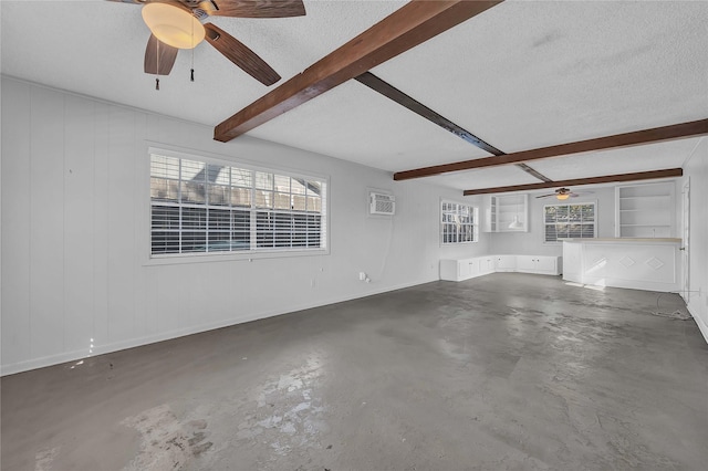 unfurnished living room with beam ceiling, an AC wall unit, concrete floors, and a textured ceiling