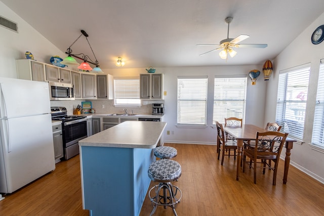 kitchen featuring lofted ceiling, sink, appliances with stainless steel finishes, and light wood-type flooring