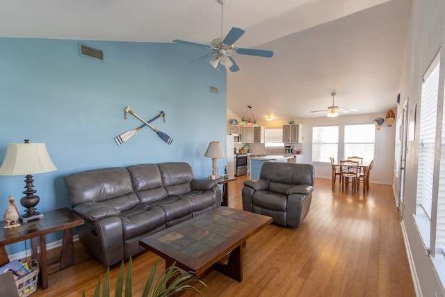 living room featuring ceiling fan, high vaulted ceiling, and light hardwood / wood-style flooring