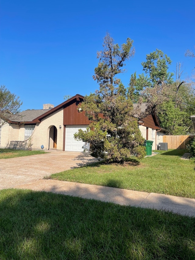 view of front of property with a front yard, a garage, and central AC unit