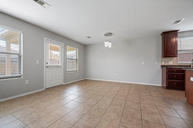 interior space with light tile patterned flooring, sink, a chandelier, and decorative light fixtures