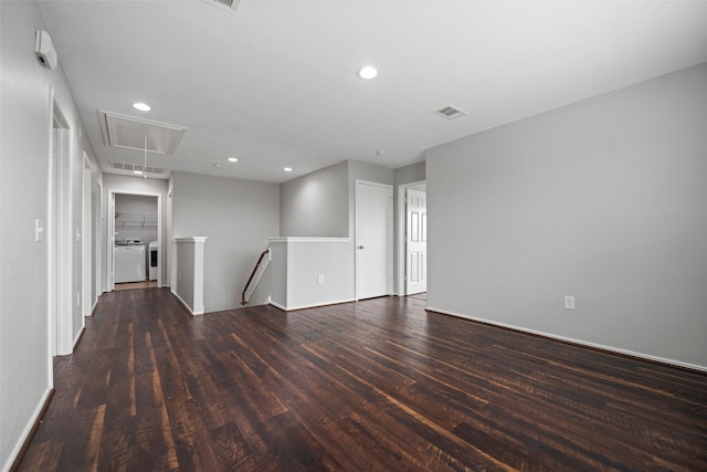 unfurnished room with recessed lighting, attic access, dark wood-type flooring, and washing machine and clothes dryer