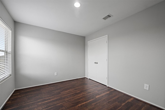 spare room featuring baseboards, visible vents, and dark wood finished floors