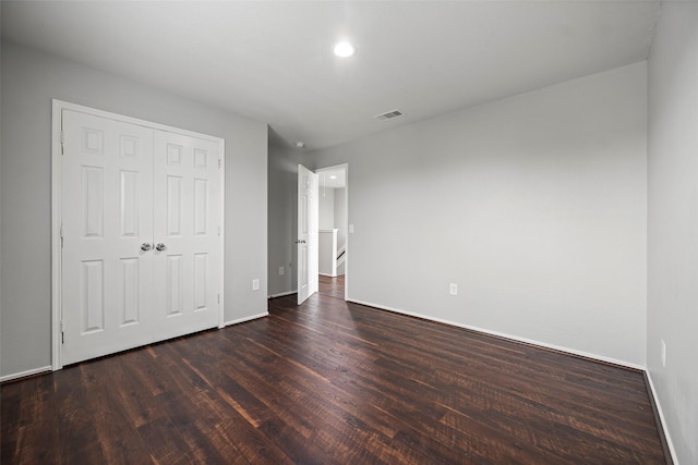 unfurnished bedroom with dark wood finished floors, recessed lighting, a closet, visible vents, and baseboards